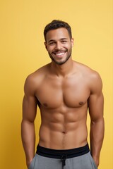Fototapeta premium Young hispanic male smiling with athletic build on yellow background