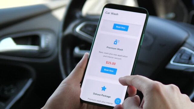 Closeup of a mans hands in a parked car using a mobile app to study and compare different car wash service packages and their prices. This scene captures the modern consumers approach to selecting