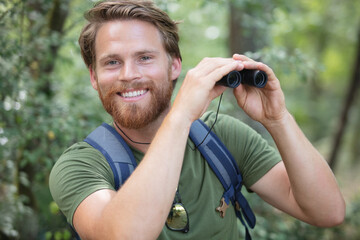 portrait of smiling male hiker binoculars in forest