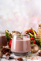 Spiced chocolate eggnog punch cocktail, served with cinnamon stick, sprinkle of nutmeg and chocolate, on cozy Christmas background 
