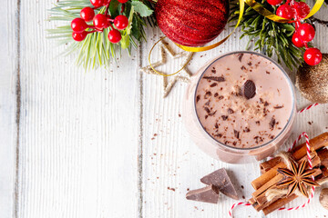 Spiced chocolate eggnog punch cocktail, served with cinnamon stick, sprinkle of nutmeg and chocolate, on cozy Christmas background 