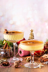 Traditional Christmas Eggnog Martini Or Brandy Alexander Cocktail with cinnamon and nutmeg, with golden Christmas decorations and bokeh effect, copy space