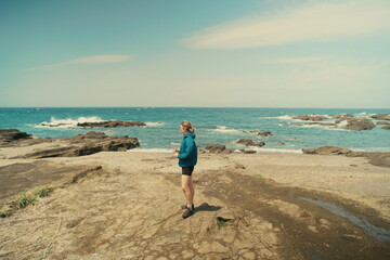 Coastal exploration scene with a woman framed against waves and sky.