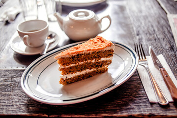 Tea time in a café with carrot cake on a wooden table
