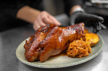 Appetizing roasted pork knuckle with a crispy golden skin, served with a side of stewed cabbage and potatoes on a rustic plate