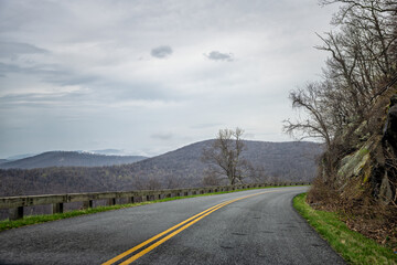 Fototapeta premium Car pov point of view driving on winding road in Blue Ridge mountains parkway in Virginia with paved asphalt road and cloudy overcast sky