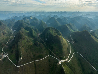 Winding Mountain Road Snaking Through Dramatic Karst Peaks in Aerial View of Guangxi China