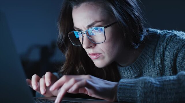 Woman Concentrating on Laptop, Typing in Low Light