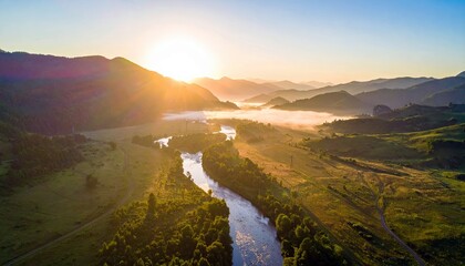 Aerial view of a river winding through a valley with mountains in the background, illuminated by the golden light of sunrise.
