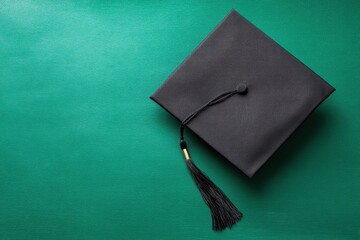 Graduation cap on green background: The iconic black graduation cap, symbol of academic achievement, rests gracefully against a vibrant green backdrop.