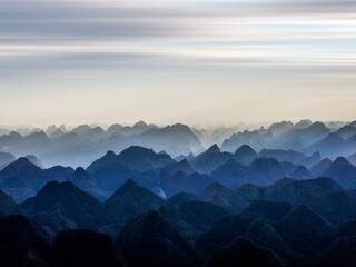 Layered Silhouettes of Karst Mountains Fading Into Misty Horizon at Sunrise in Guangxi China