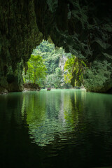 Perfect Mirror Reflection of Cave Entrance and Lush Vegetation on Calm Underground River in Guangxi China
