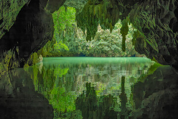 Perfect Mirror Reflection of Cave Entrance and Lush Vegetation on Calm Underground River in Guangxi China