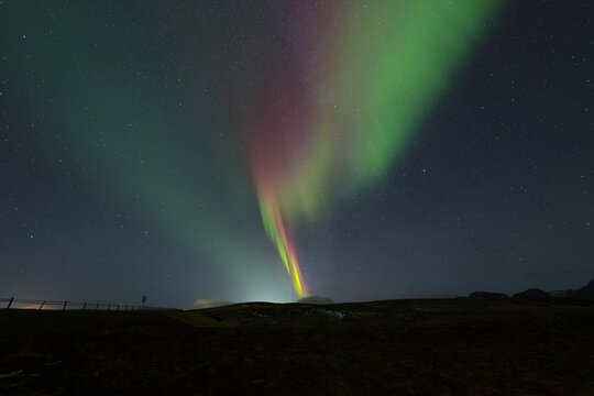 View of the celestial dance of the aurora borealis paints the night sky with vibrant greens and reds over the dark landscape, Snaefellsnes, Eyja- og Miklaholtshreppur, Iceland.