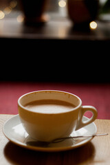 yellow cup of coffee on a saucer on a cozy cafe table