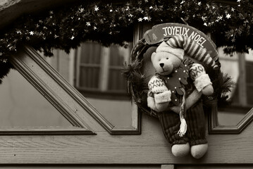 Alsace, France. Christmas wreath decoration on house door with teddy bear holding Christmas tree....