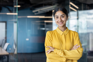 Portrait of a young Indian businesswoman in a yellow shirt with her arms crossed on her chest...