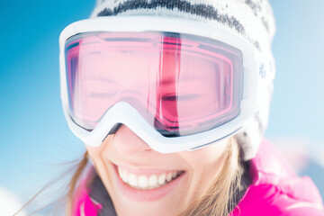 Close-up of a female skier wearing reflective ski goggles, looking into the distance. Winter sports portrait with snowy mountains reflected in lenses, concept of adventure and focus.