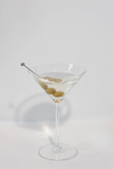 A refreshing martini cocktail with green olives. The clear liquid is in a classic martini glass, perfect for a special occasion.
