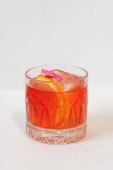 A vibrant cocktail in a elegant glass, garnished with a citrus slice and flower