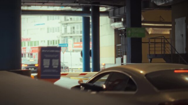 A car is stopping in front of an electronic entry machine with a barrier at a parking lot. The machine provides information about the parking duration as the car prepares to leave