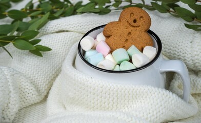 Gingerbread man cookie relaxing in a warm cup of cocoa with colorful marshmallows