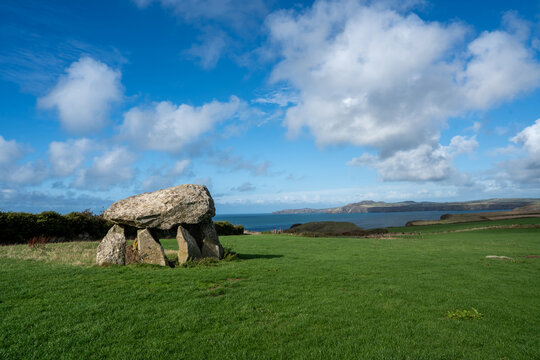 View of Pentre Ifan Burial Chamber, a Neolithic dolmen standing proudly on a vibrant green hill under a vast sky, St. Davids, Wales, United Kingdom.