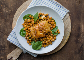 Pan-seared cod served with chickpeas and fresh spinach on a white plate