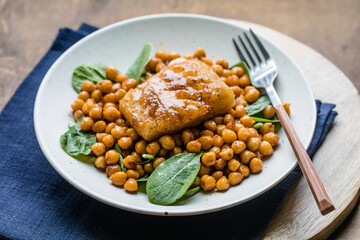 Pan-seared cod served with chickpeas and fresh spinach on a white plate