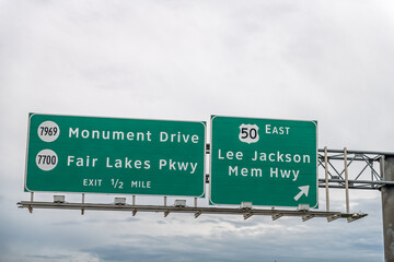 Fairfax county highway in Northern Virginia with exit isolated sign against cloudy sky for east Lee Jackson Memorial Highway and Monument drive