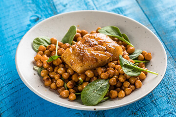 Pan-seared cod served with chickpeas and fresh spinach on a white plate