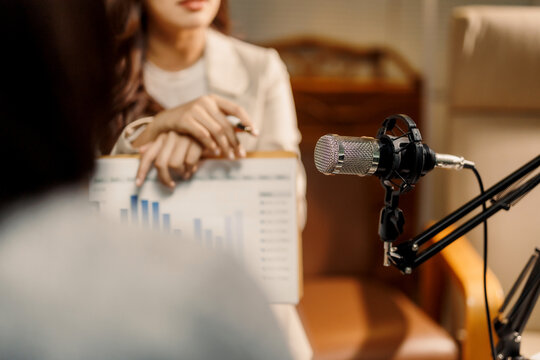 Woman's hand pointing at bar chart data during a recording session, discussing economic trends and market analysis on air