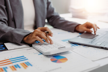 Business professional hands performing calculations on a desktop calculator while working with a...