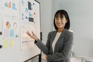 Confident businesswoman smiling, presenting business data analysis and financial charts during a corporate office meeting or presentation
