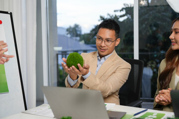 Man holding a moss ball during a corporate meeting, symbolizing environmental responsibility and sustainable business practices