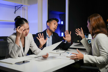 Colleagues experiencing stress and conflict, discussing problematic project data in a tense office meeting late at night