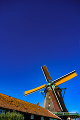 Vertical shot of a Dutch windmill offering ample copy space in the deep blue sky.