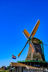 Symbol of the Netherlands: Traditional windmill and the Dutch flag waving in the wind
