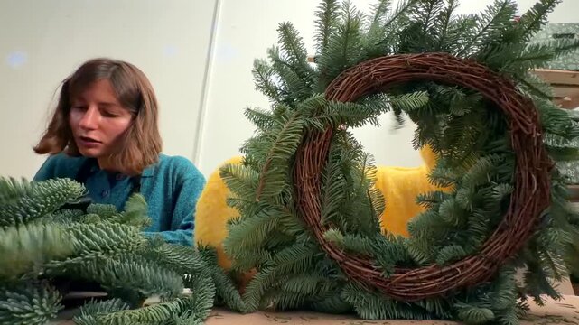 Preparing grapevine base with evergreen sprigs on table