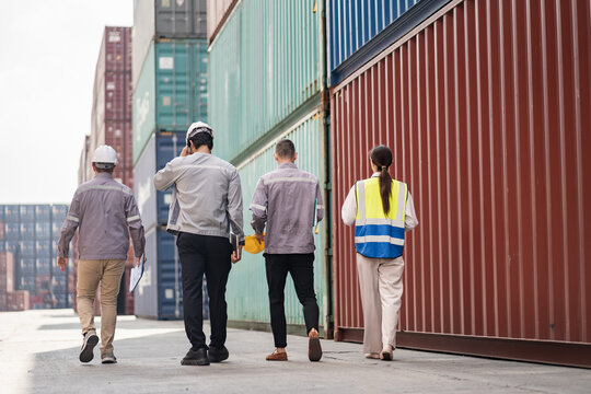 Back engineer walking and worker team working in logistic terminal of container cargo, Diverse construction team in safety gear outdoors	