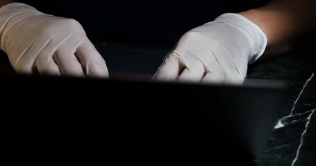 A hacker is using a computer to steal information. A hand wearing white gloves is typing to search for information.