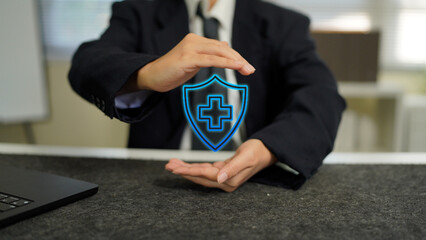Businessman holding digital shield with medical cross icon, symbolizing health insurance protection, healthcare technology, safety, and innovation in modern digital healthcare.