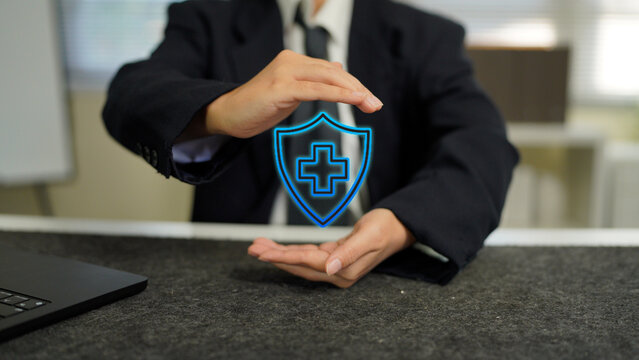 Businessman holding digital shield with medical cross icon, symbolizing health insurance protection, healthcare technology, safety, and innovation in modern digital healthcare.