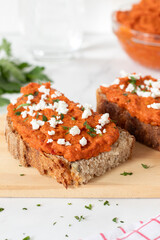 Homemade ajvar (red pepper spread) on bread slices with cheese and fresh parsley. Close-up.