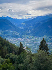 Scenic view over Merano (Meran) and the Burgraviato in the Adige Valley, Italy, with the Vinschgau (Val Venosta) and the Oetztal Alps beyond; towns, orchards and mountains under a cloudy sky