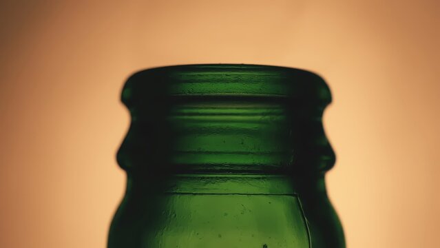 Green glass bottle neck macro closeup against light