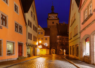 Fototapeta premium Markus Tower and Roeder Arch in Rothenburg ob der Tauber Germany illuminated at night with historic houses