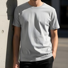 Young man in a plain grey t-shirt and black pants leaning against a concrete wall, ideal for a casual apparel design mockup