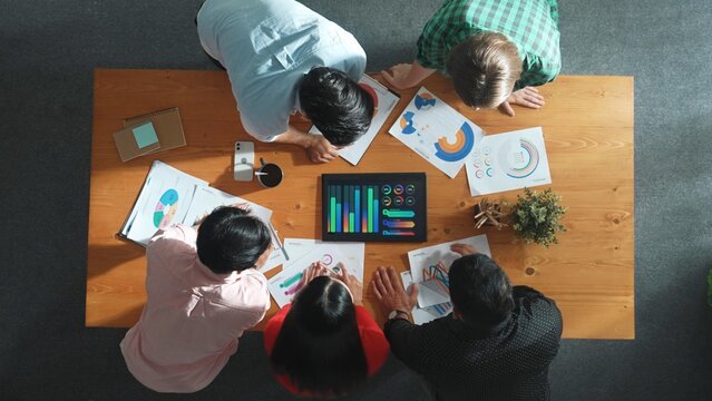 Top view of skilled business team looking financial graph and brainstorming marketing idea. Closeup of group of diverse people looking at stock market statistic from tablet. Start up. Convocation.