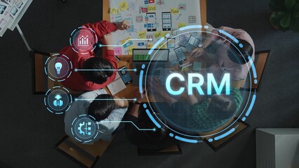 Overhead view of a team working on CRM system development. The digital interface displays concepts, analytics, and project planning tools, enhancing collaboration. Raster